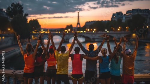 Diverse group of athletes celebrating victory on a Parisian bridge, showing unity and joy, with the Seine River reflecting the city lights