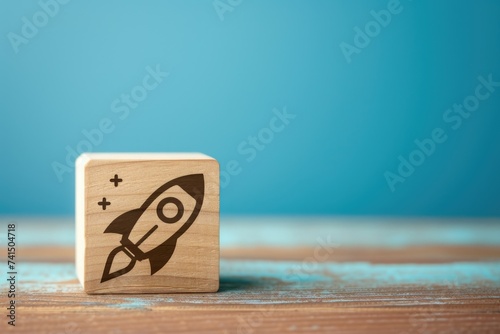 Wooden block with rocket printed on it, startup and business concept, blue background.