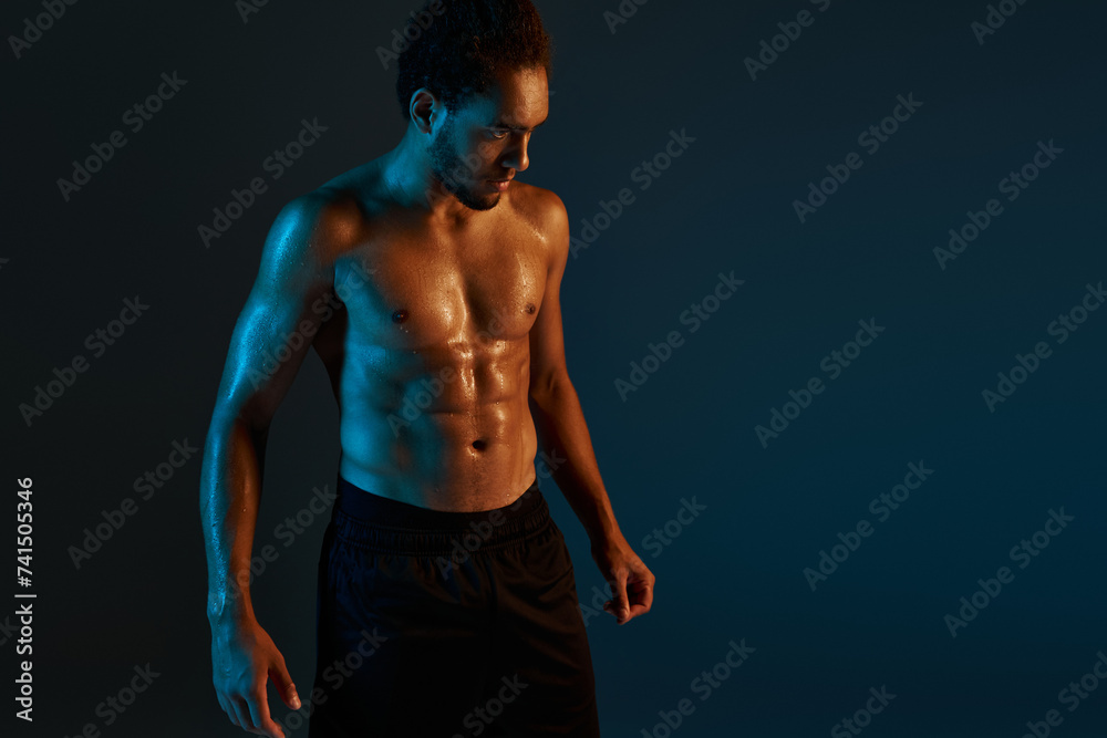handsome african american man in black shorts posing in gym during training surrounded by light