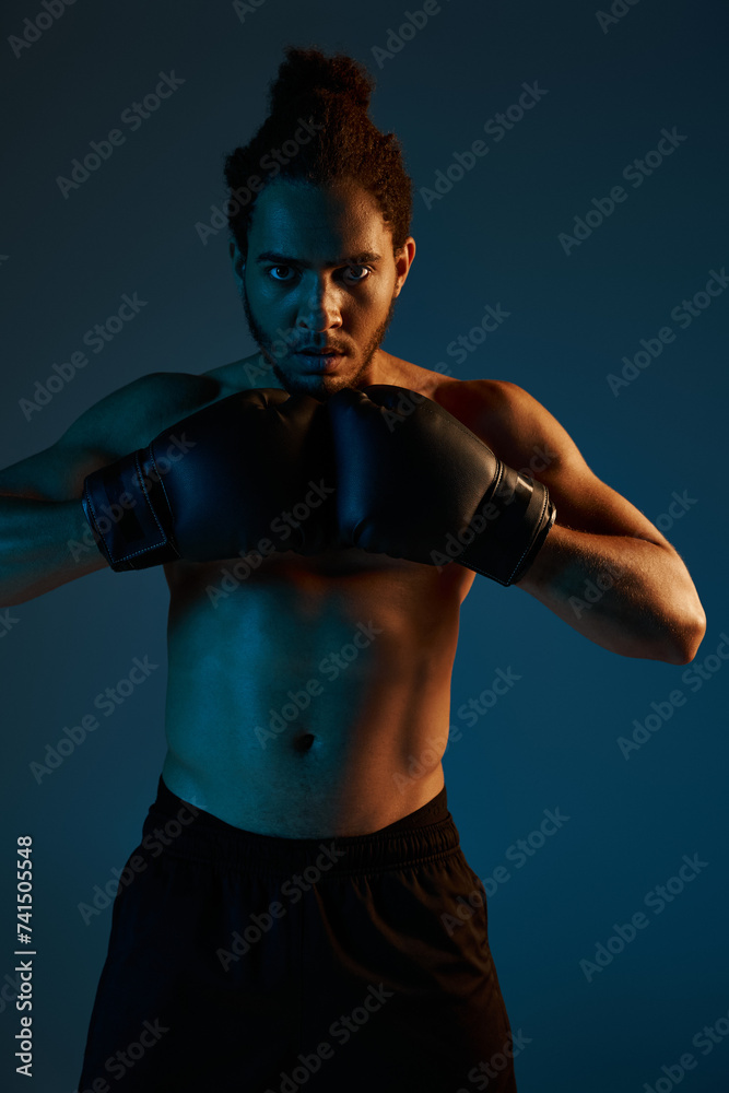 handsome young african american man in black shorts with boxing gloves posing and looking at camera