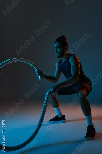 attractive young african american man in black sport uniform training actively with battle ropes © LIGHTFIELD STUDIOS