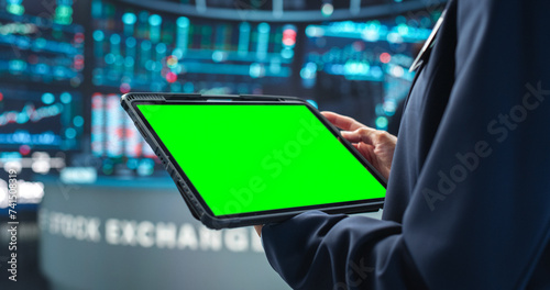 Person Holding a Tablet Computer with Green Screen Mock Up Display. Stock Exchange Application Template. Banker Monitoring Financial and Business Opportunities