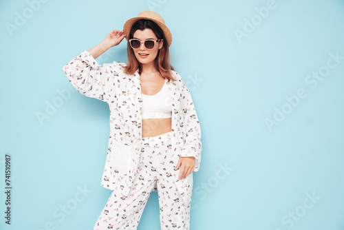 Young beautiful smiling female in trendy summer costume clothes. Carefree woman posing near blue wall in studio. Positive model having fun indoors. Cheerful and happy © halayalex