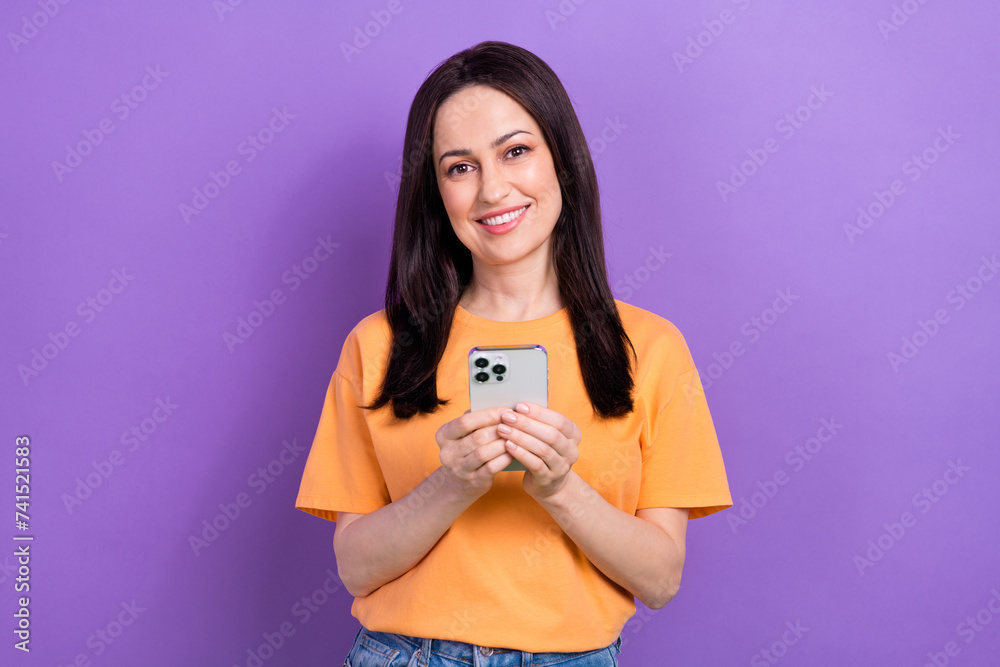 Portrait of toothy beaming intelligent girl wear oversize t-shirt holding smartphone writing email isolated on violet color background