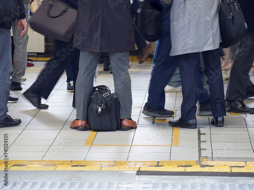 冬の朝の混雑している通勤電車の駅のホームの乗客の様子