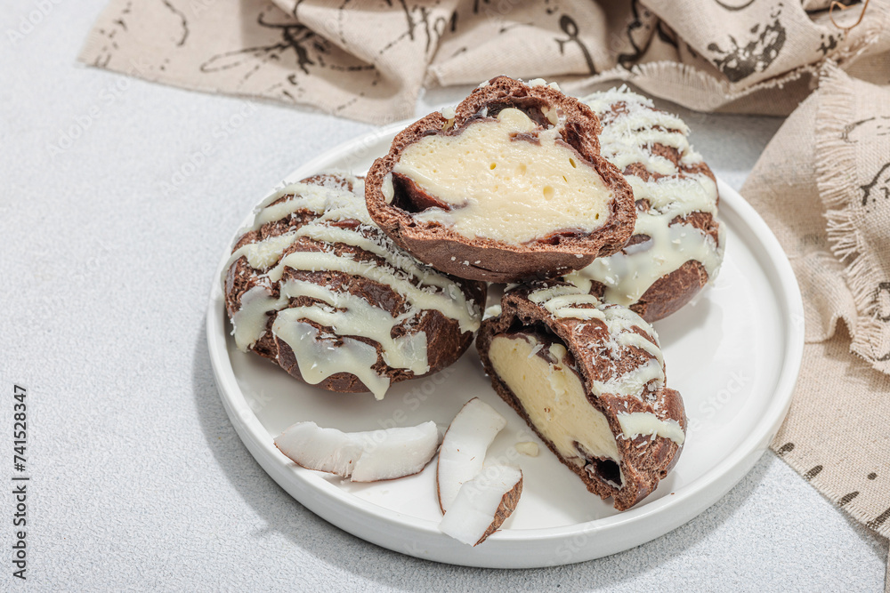 Profiteroles choux pastry buns with coconut cream served in tropical style. Palm leaves