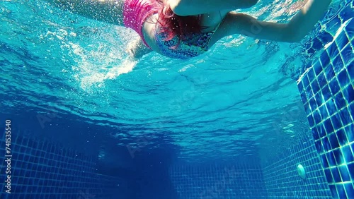 Girl swimming underwater in the pool photo
