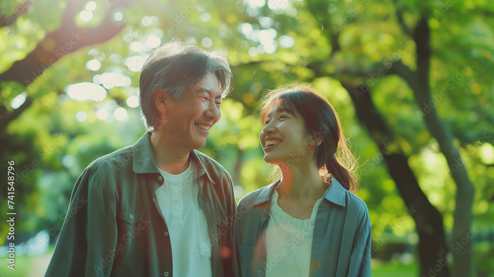 Fototapeta premium 50代の日本人夫婦が新緑のきれいな公園を散歩している仲睦まじい様子