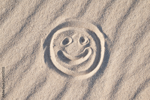 Happy smiley drawn on the white wavy sand, close up. Concept of good emotions, happiness, positive vibes photo