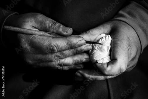 Quadro em tela Black and white close-up photo of a craftsman hands carving a meerschaum tobacco pipe