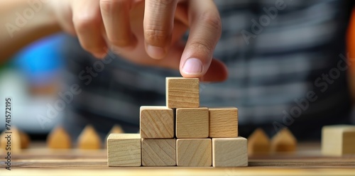Visionary Structure: Hands Delicately Position Wooden Blocks, Forming a Visual Representation of Business Strategy and Action Plan.