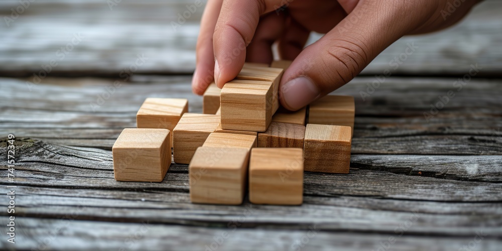 Crafting Development Path: Hands Thoughtfully Organize Wooden Blocks, Constructing a Tangible Business Strategy Representation. Crafting Development Path: Hands Thoughtfully Organize Wooden Blocks, Constructing a Tangible Business Strategy Representation.