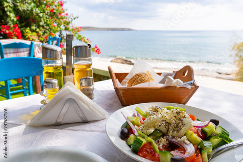 Typical Greek dishes served on a Greek tavern table with the Aegean Sea in the background and bright summer day in the south of Crete