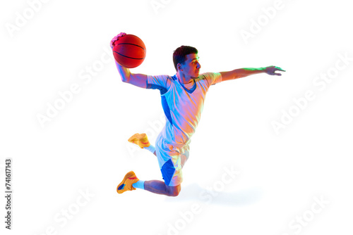 Focused basketball player in game progress doing powerful dunk in motion against white studio background in neon light. Concept of professional sport, energy, strength and power, match, tournament. © Lustre
