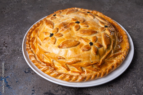 Rustic homemade round meat pie with golden crust, isolated on white background