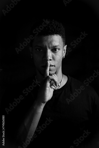 Obraz na płótnie Serious young man making silence gesture. black and white photography w salonie