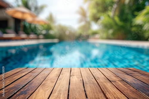 Empty beautiful wooden tabletop on background blurred view of swimming pool in summer holiday   space for your text or product