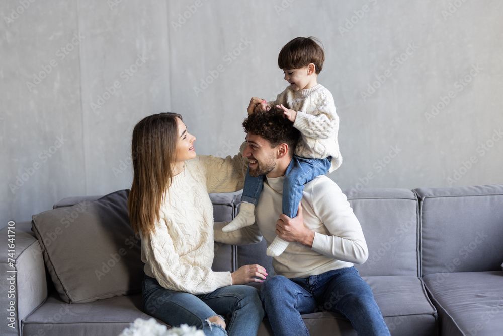 Happy young Caucasian family with small son relax on sofa in living room