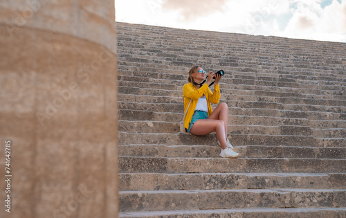 A woman tourist with a camera in the Acropolis on an excursion.