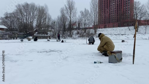 Winter ice fishing. A fishingman holds a fishing rod near a hole in the ice. The man was fishing in the fresh air. A boy's winter hobby. High quality 4k footage. High quality 4k footage photo