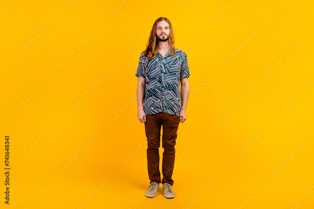Full length photo of serious confident guy wear print shirt walking empty space isolated yellow color background Full length photo of serious confident guy wear print shirt walking empty space isolated yellow color background