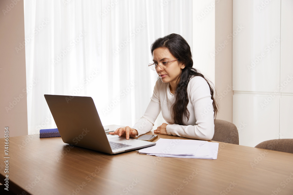 pretty woman in glasses using laptop and communicates with customer on internet at home pretty woman in glasses using laptop and communicates with customer on internet at home