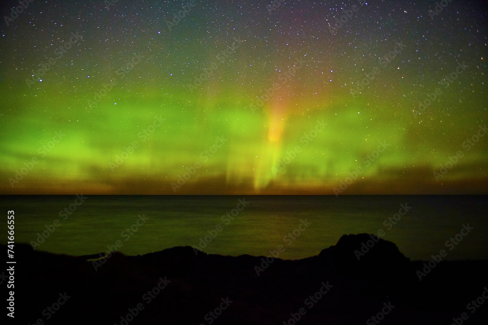 Aurora Borealis Over Rocky Beach and Starry Sky in Michigan