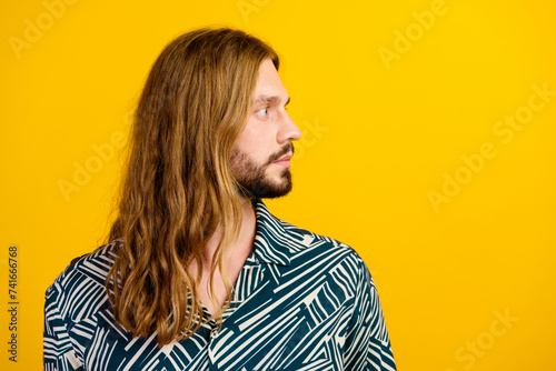 Photo of positive funky guy wear print shirt looking empty space isolated yellow color background