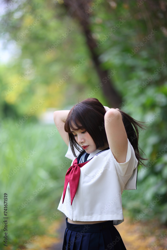 Japanese high school student tied her hair up in park with tree background Japanese high school student tied her hair up in park with tree background