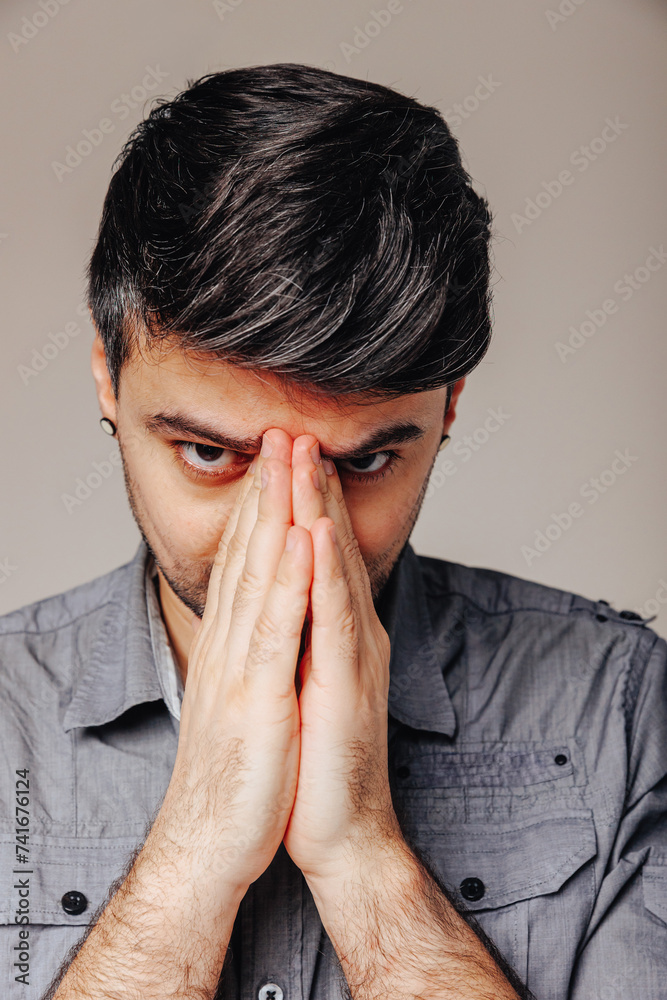 Man folding his hands in prayer by his face. Man folding his hands in prayer by his face.