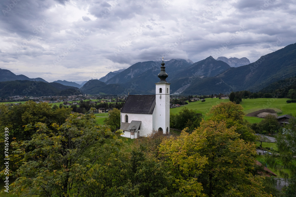 Aerial drone view of Wallfahrtskirche St. Nikolaus with Golling an der Salzach in background at cloudy day, Golling an der Salzach, Salzburg, Austria. Aerial drone view of Wallfahrtskirche St. Nikolaus with Golling an der Salzach in background at cloudy day, Golling an der Salzach, Salzburg, Austria.