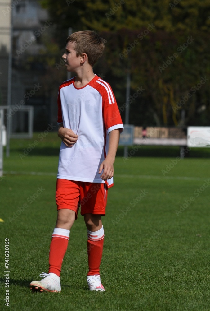 a boy in a sports football suit stands on a football field