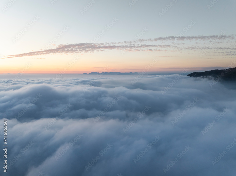 Aerial view of mountain range surrounded by low clouds at sunset and the Amalfi Coast in background as seen from the plane, Salerno, Campania, Italy. Aerial view of mountain range surrounded by low clouds at sunset and the Amalfi Coast in background as seen from the plane, Salerno, Campania, Italy.
