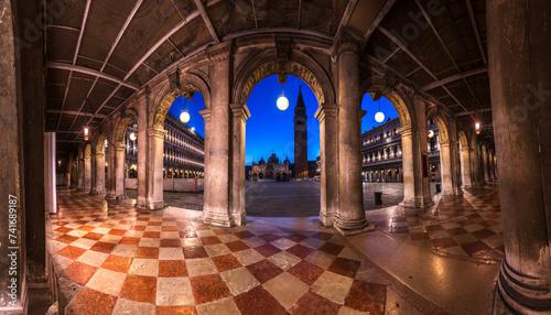 Tranquil scene of St. Marks Square at dusk, framed by the arches of Museo Correr building.