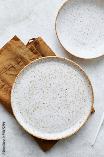 Two empty plates and brown napkin on light table. Top view, close up, flat lay.