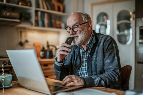 Photograph of a happy middle-aged man Wear glasses to talk on a cell phone Looking at laptop using computer Call customer service on your smartphone.