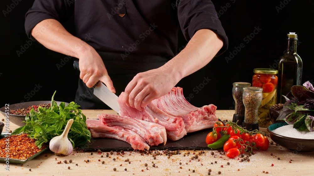 Chef marinates meat on a dark background. Pork ribs, fresh meat, marinated. Restaurant menu concept, recipes and cooking delicious food.