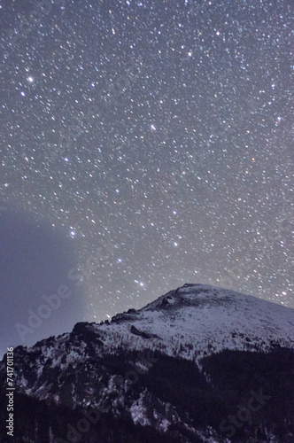 Highland mountain covered in snow under starry night sky atmosphere