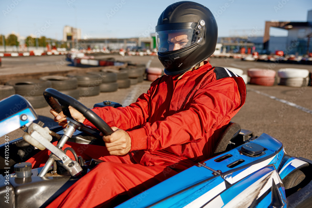 Concentrated karting pilot ready to start championship in outdoor go-karting circuit