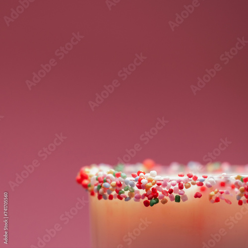 Close-up of a cocktail in a glass with a sugared rim of multi coloured hundreds and thousands