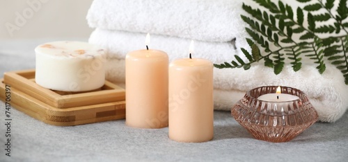 Spa composition. Burning candles  soap and towels on soft grey surface