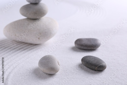 Zen garden stones on white sand with pattern, closeup