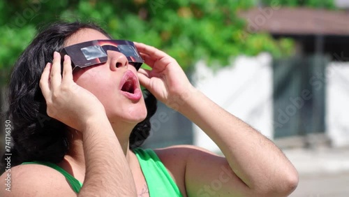 Happy young latina woman with solar eclipse glasses, watching a solar eclipse photo