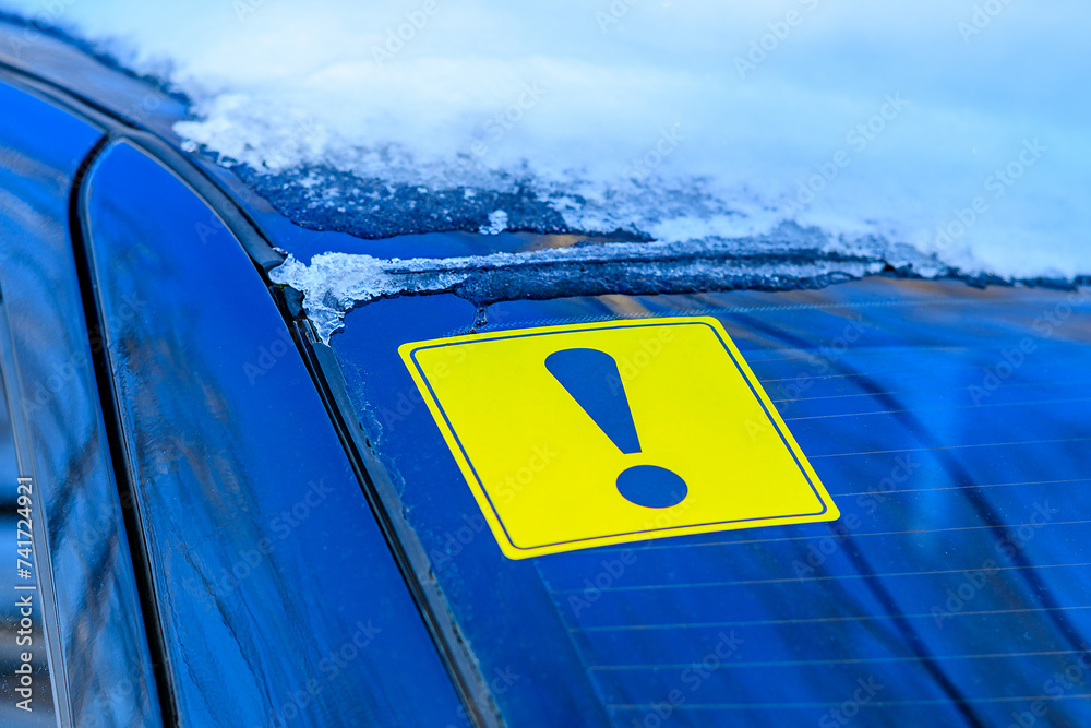 Yellow exclamation mark in selective focus on the rear window of a car