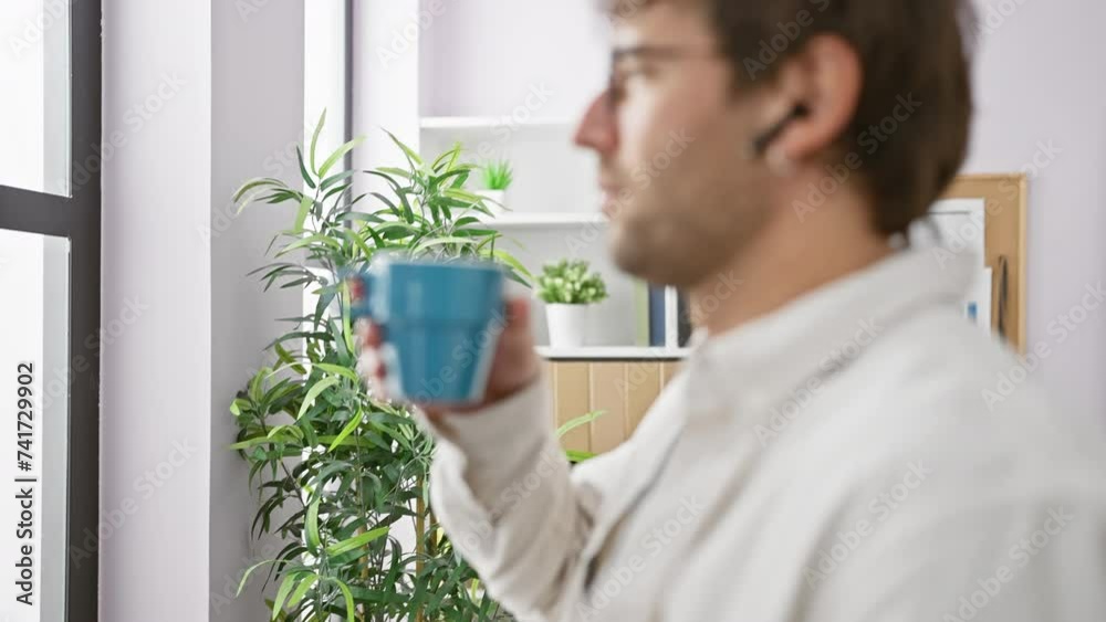 A young man with a beard sips coffee in a modern office setting, evoking a sense of relaxed professionalism. A young man with a beard sips coffee in a modern office setting, evoking a sense of relaxed professionalism.