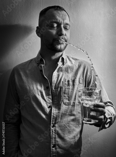 Image of a stylish man who ironically spits into a glass. Fashion concept. photo