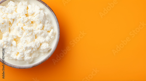 Cottage cheese in a bowl on orange background. Top view