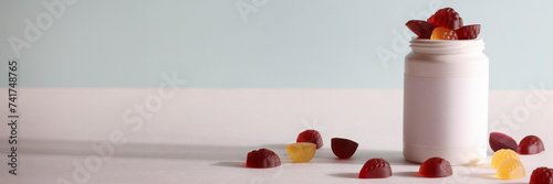 chewable supplements, nutritional gummies, edible health concept. colorful marmalades and bottle for your mock up or design. copy space banner photo