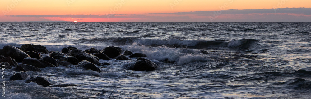 Obraz premium breakwater with surf at sunset.