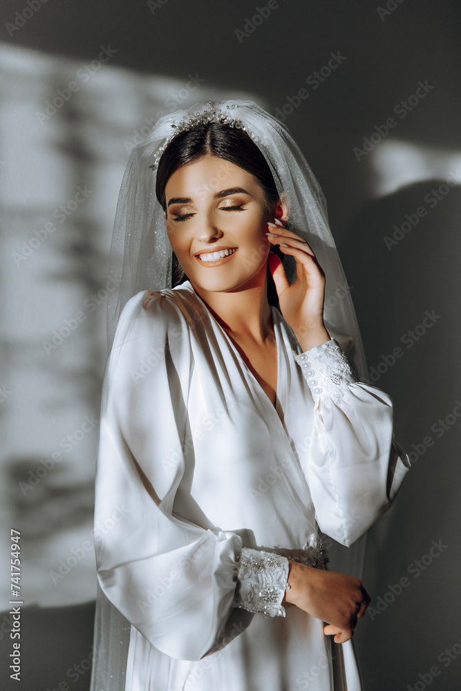 portrait of an incredibly beautiful girl bride in a white robe in the bedroom, the bride poses in the morning before the wedding ceremony. portrait of an incredibly beautiful girl bride in a white robe in the bedroom, the bride poses in the morning before the wedding ceremony.